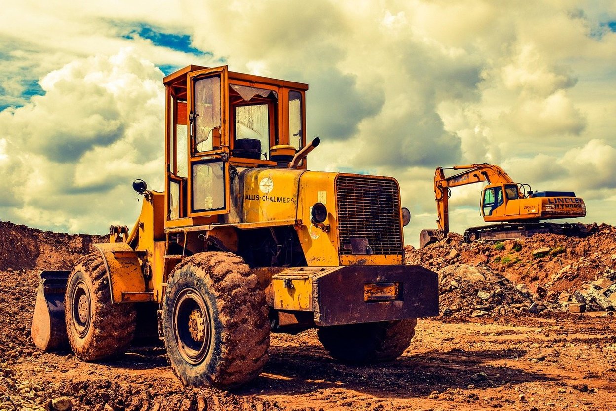 A yellow wheel loader and excavator on a construction site