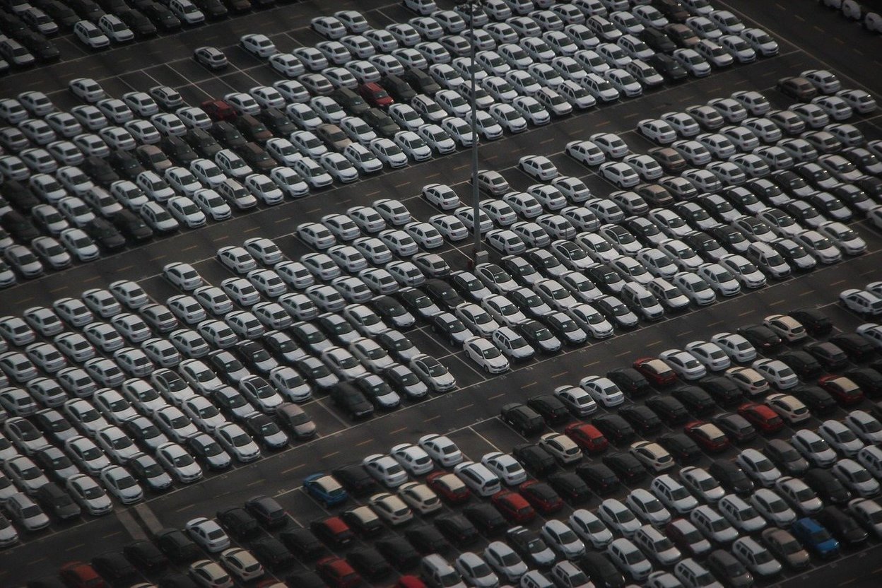 Rows of vehicles parked in a large auction lot seen from above