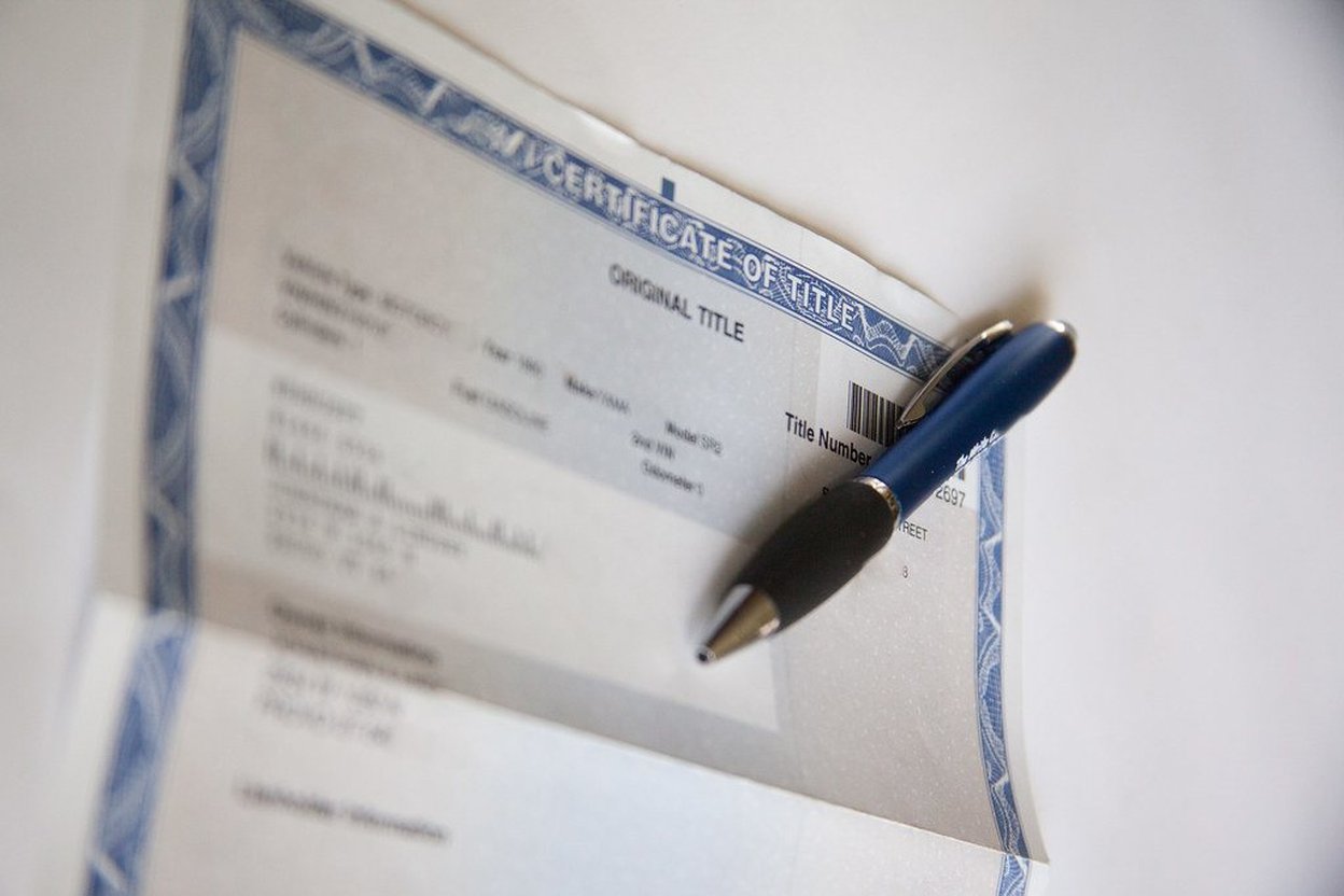 Blue pen rests on a vehicle title certificate.