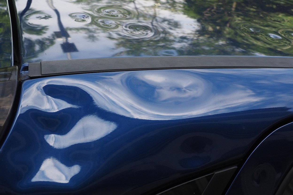 A pickup truck with hail dents on its hood and roof
