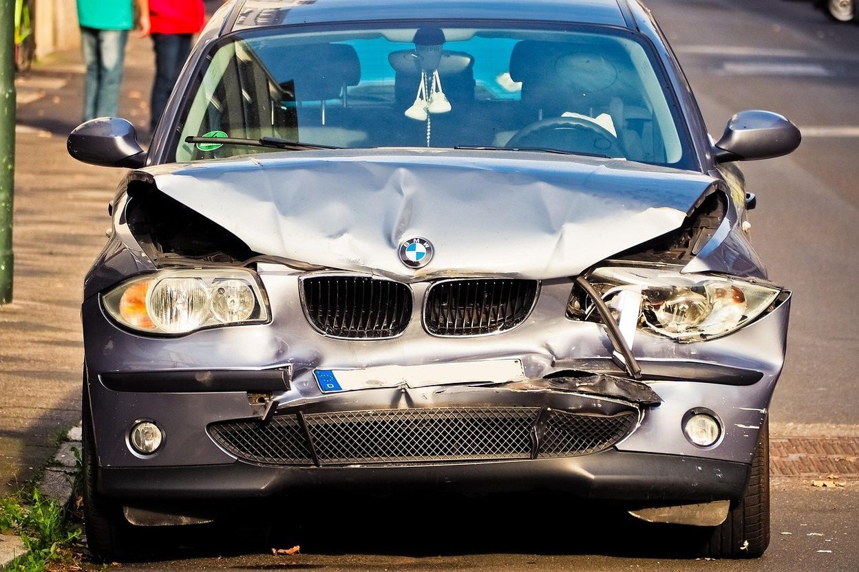 Late-model pickup truck with front-end damage from a deer strike: smashed grille, dented hood, and crumpled bumper.