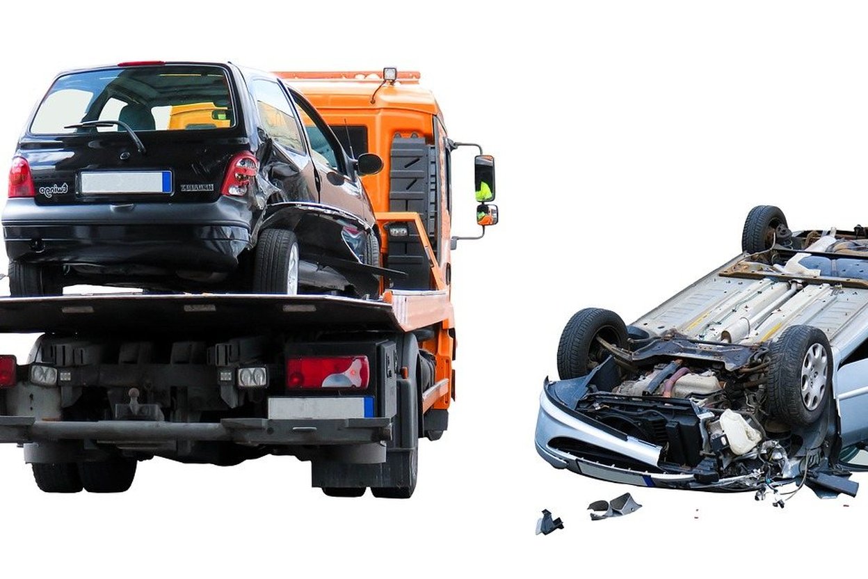 Towed car and wrecked vehicle on white background.