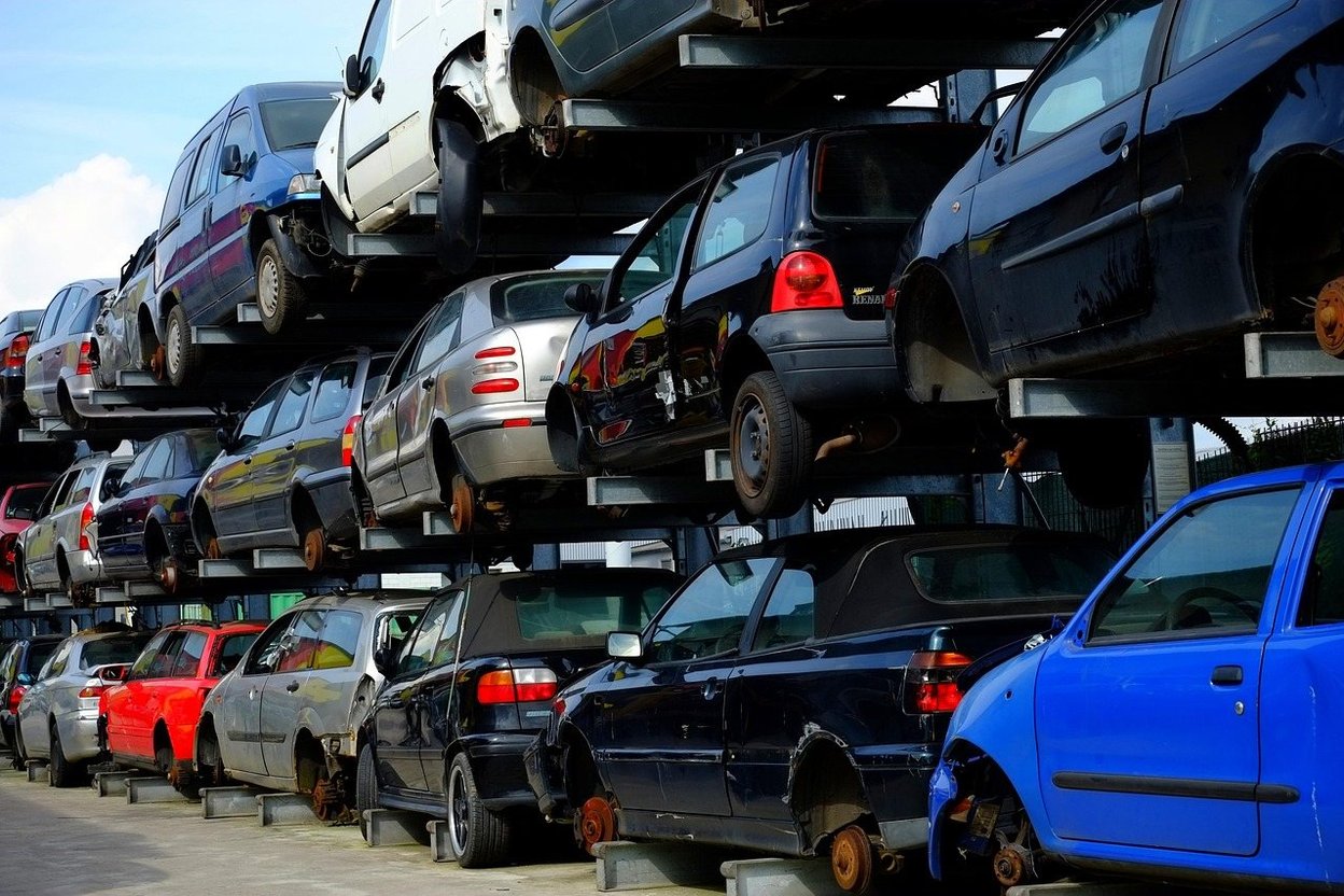 Stacked cars in a salvage yard, some missing parts.